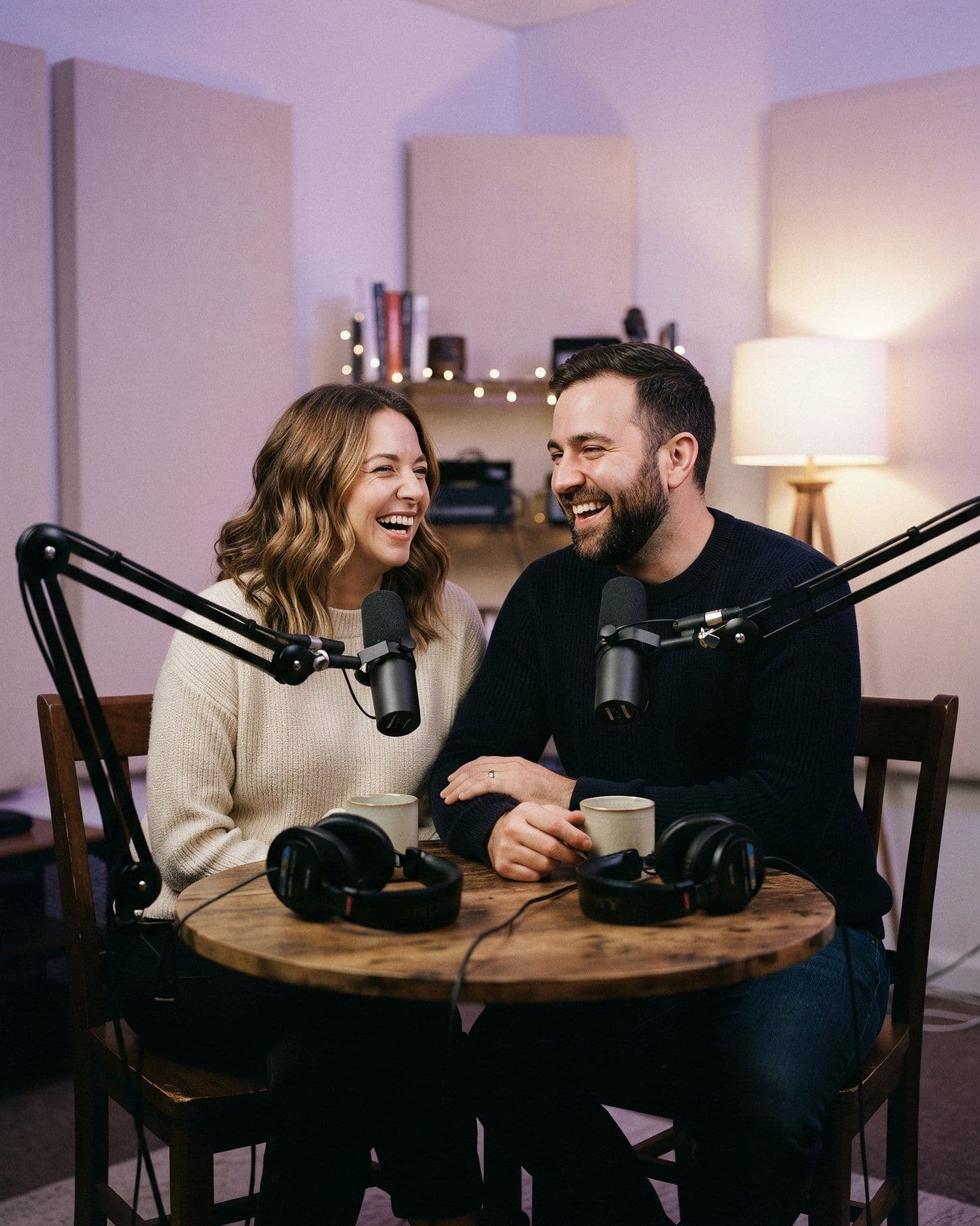Two of the network’s hosts laughing together at the studio table after a recording